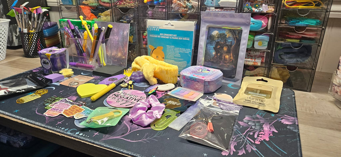 A tabletop display of various colorful accessories and stationery items, including a yellow plush toy, purple hair bows, sticker sheets, pens, and packaged accessories, set against a background of storage drawers.
