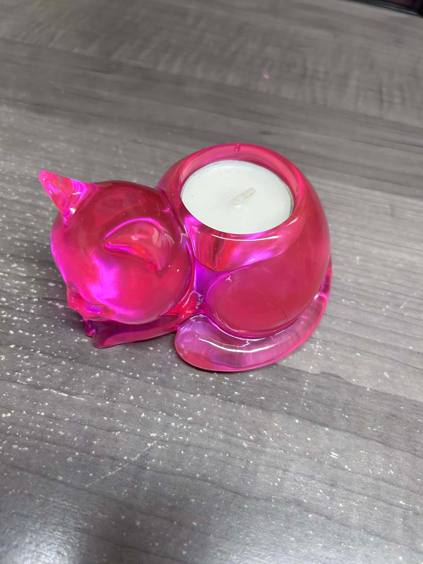 Pink cat candle holder with a white candle on a gray surface