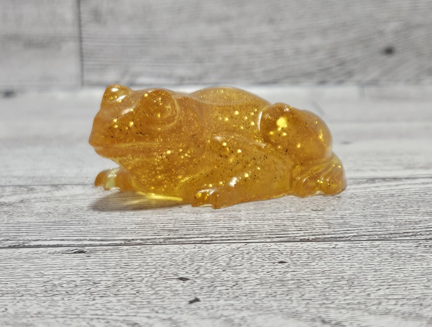 Transparent amber-colored frog figurine on a wooden surface