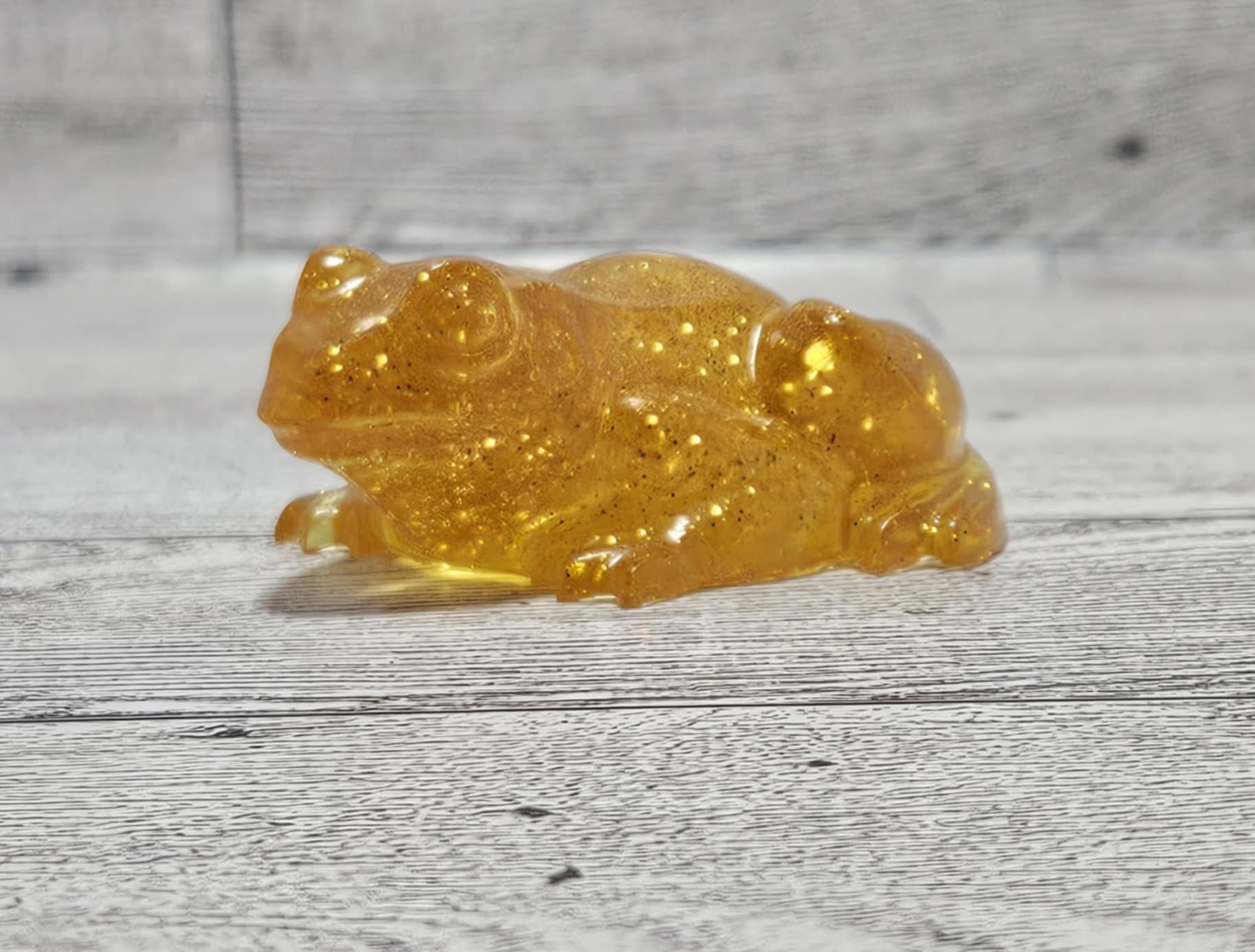Transparent amber-colored frog figurine on a wooden surface