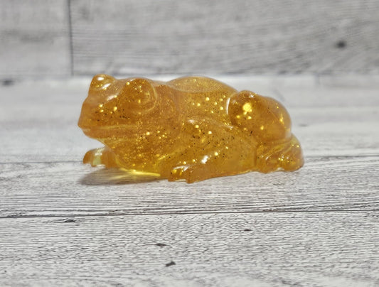 Transparent amber-colored frog figurine on a wooden surface