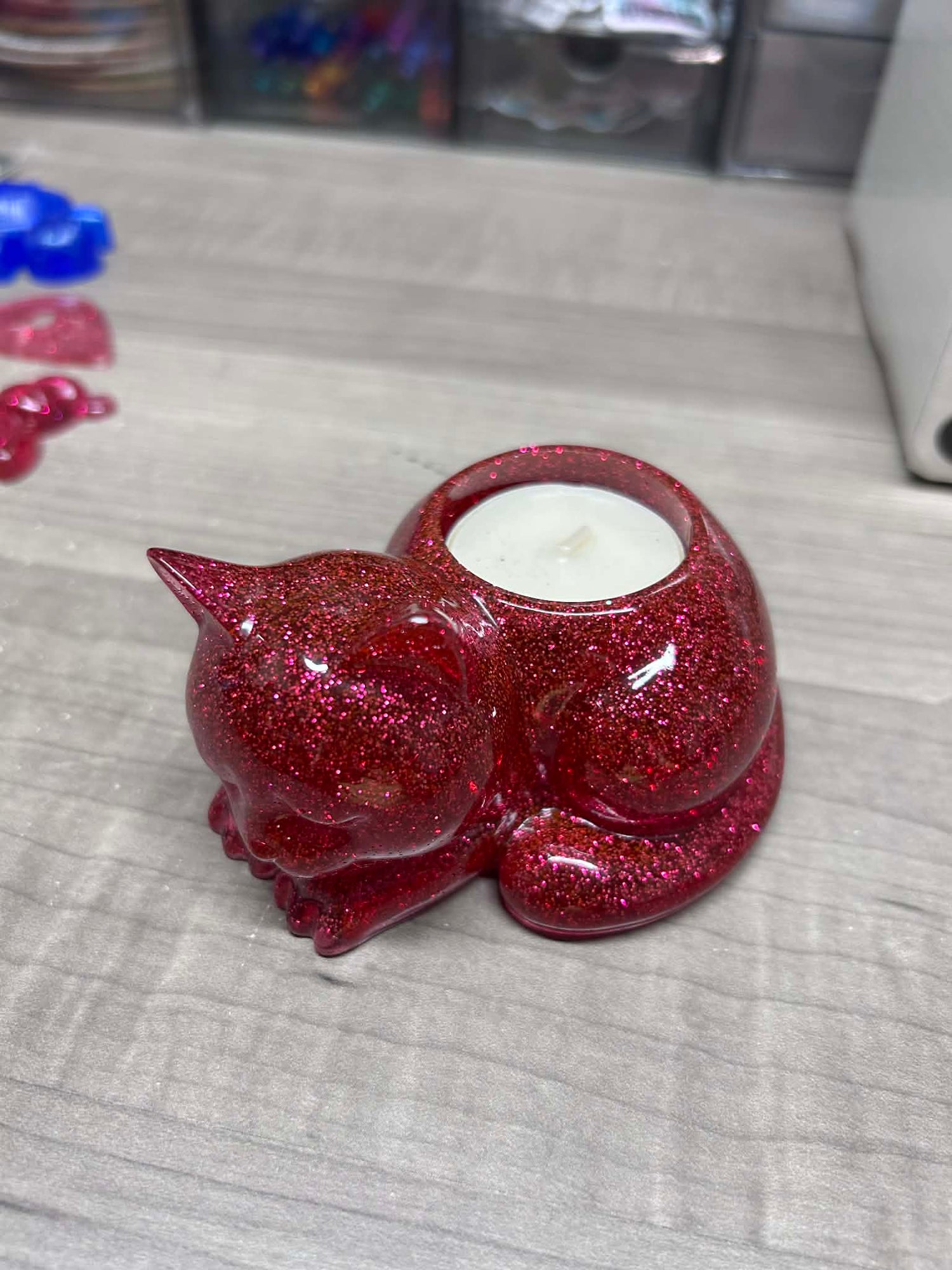 Red glittery cat-shaped candle holder on a gray surface