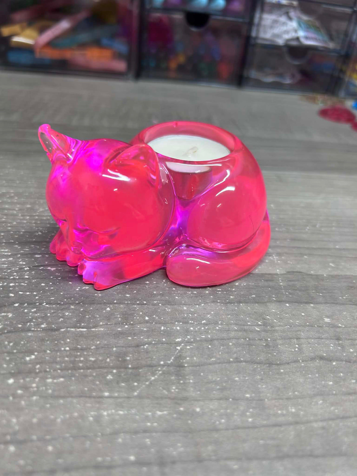 Pink plastic container with a small candle inside on a gray surface