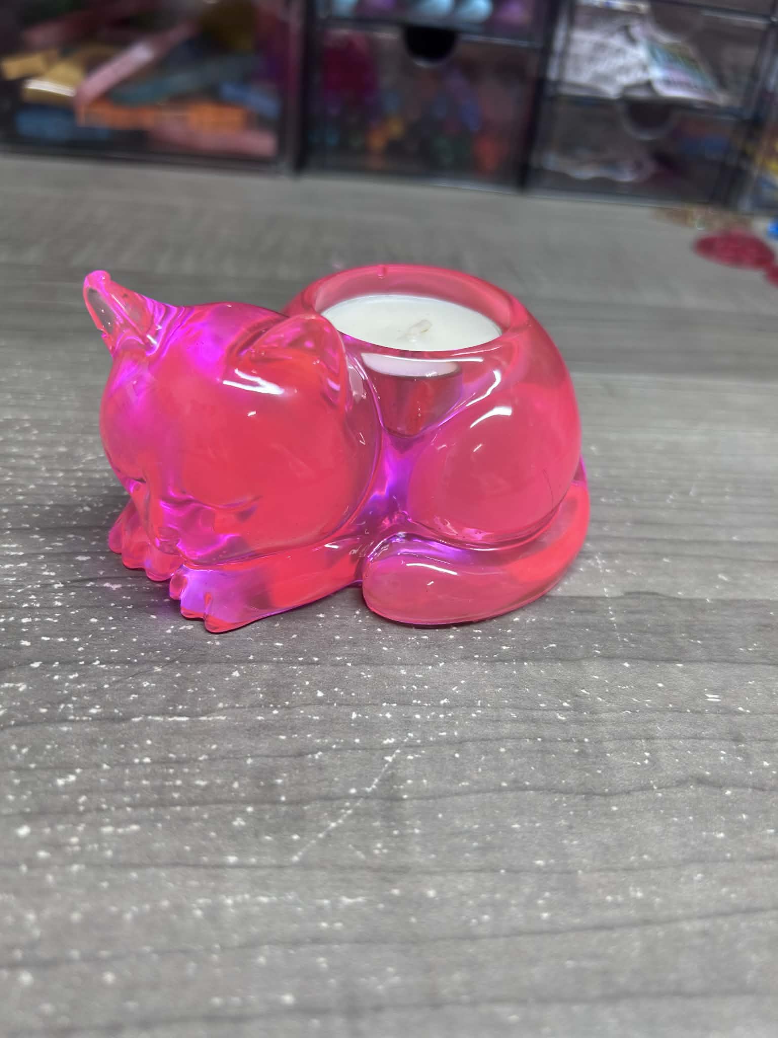 Pink plastic container with a small candle inside on a gray surface