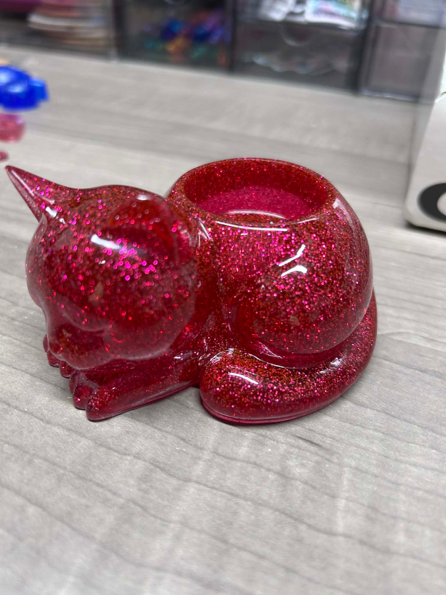 Red glittery cat-shaped container on a gray surface
