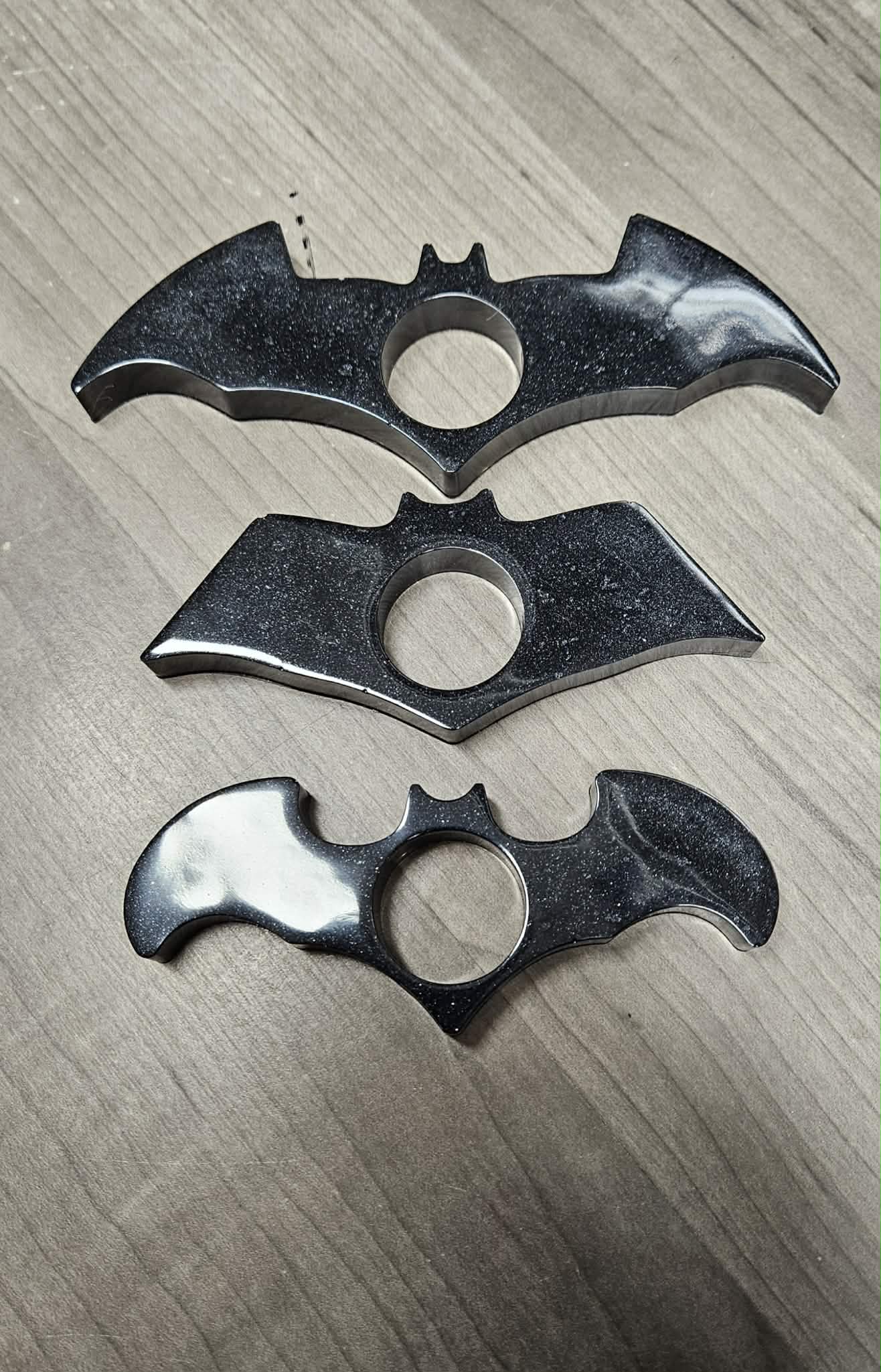 Three bat-shaped page holders on a wooden surface