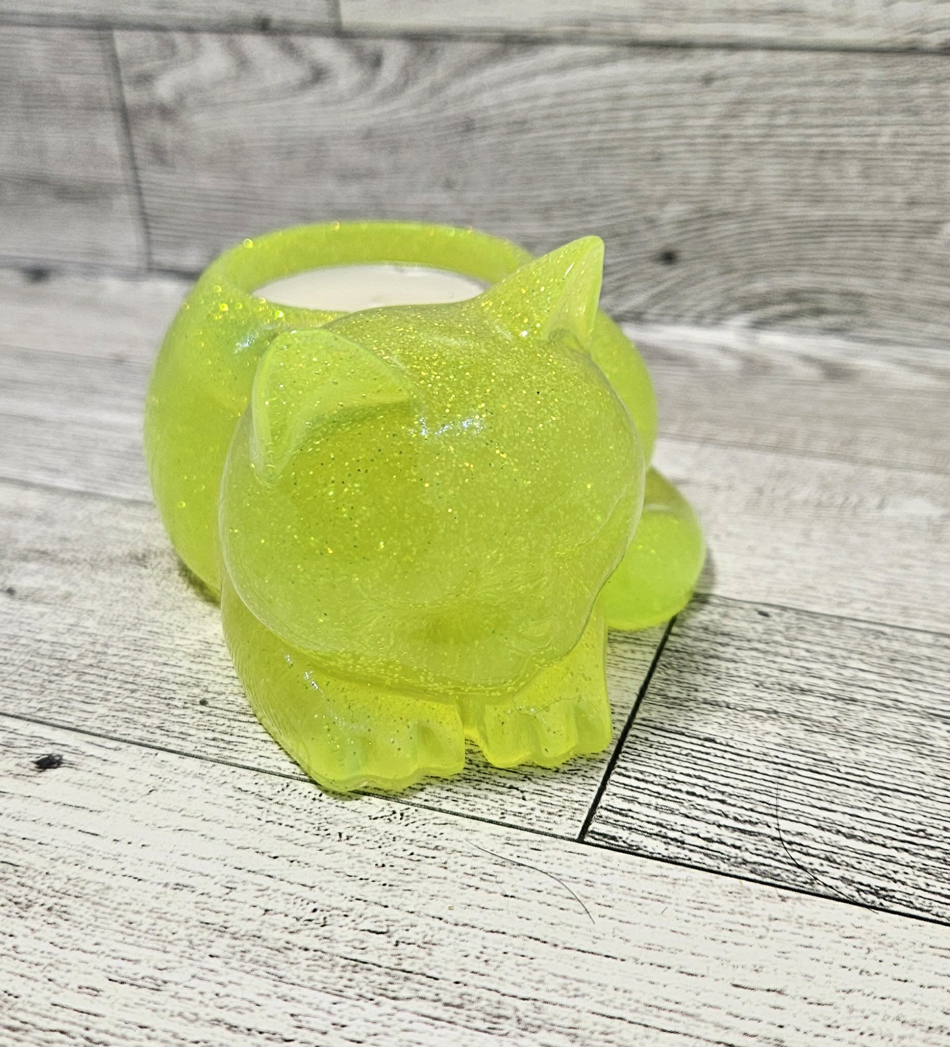 Green cat-shaped candle holder on a wooden surface