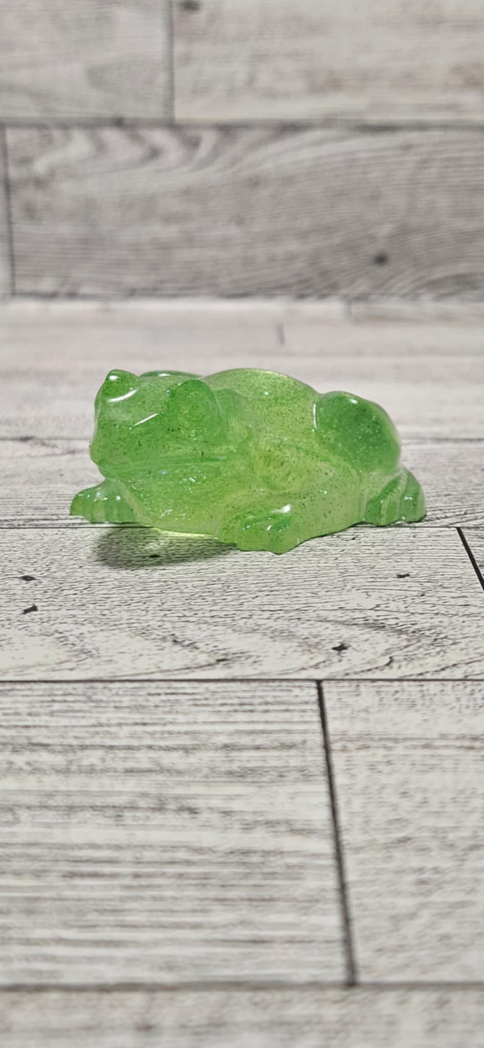 Green frog figurine on a wooden surface