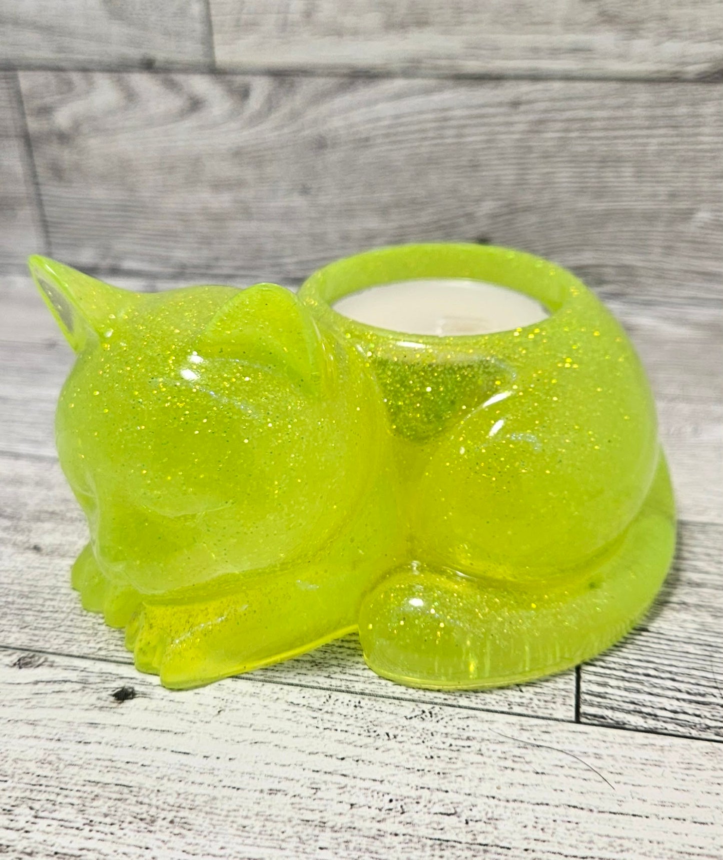 Green glittery cat-shaped candle holder on a wooden surface