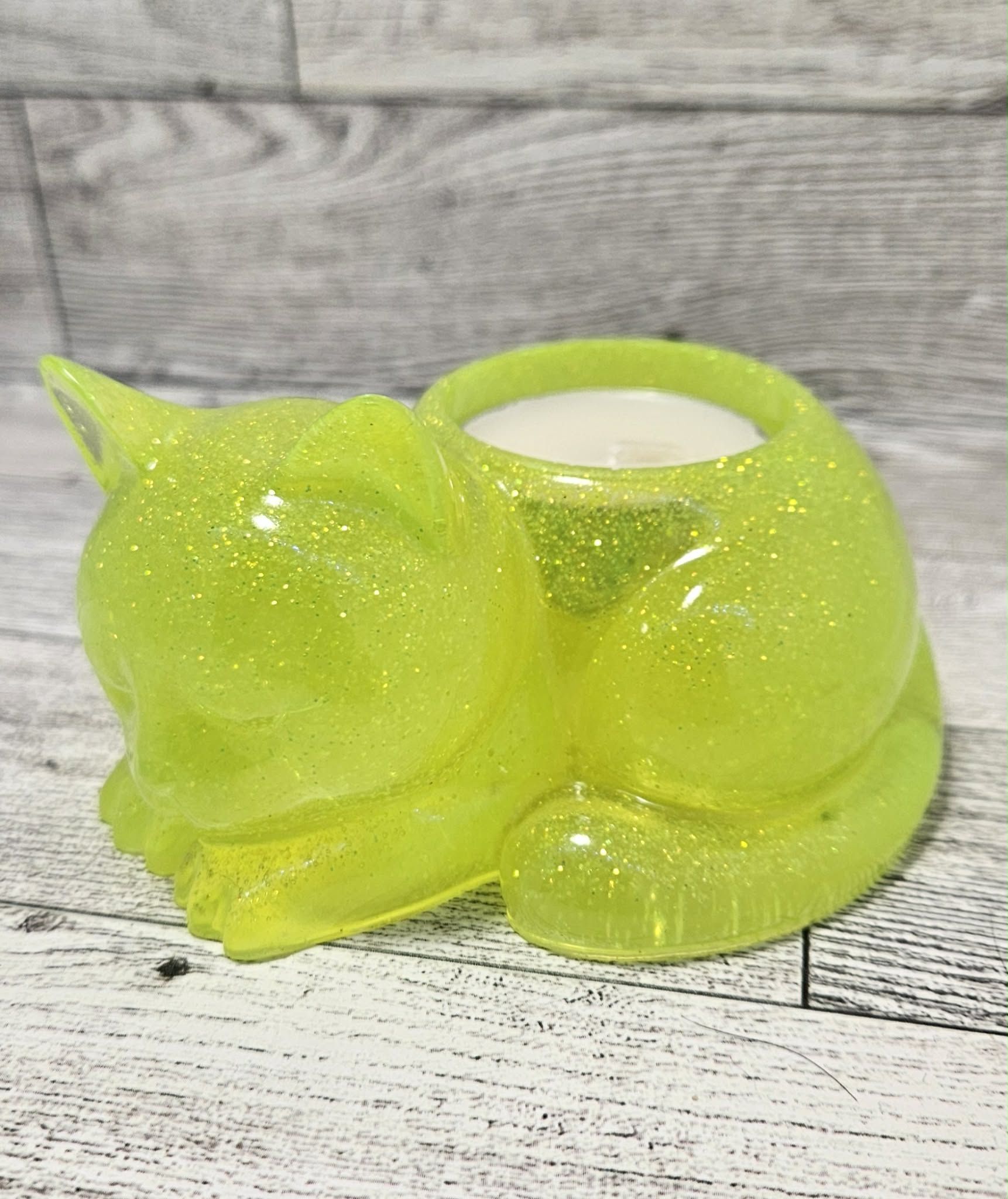 Green glittery cat-shaped candle holder on a wooden surface