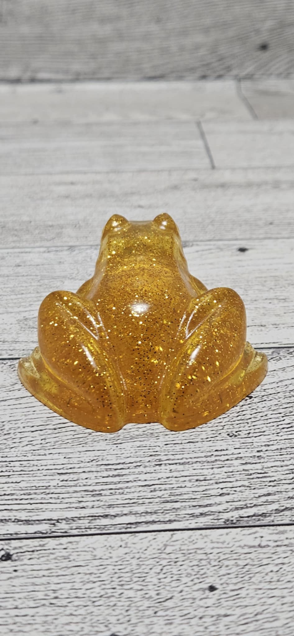 Gold glittery frog figurine on a wooden surface