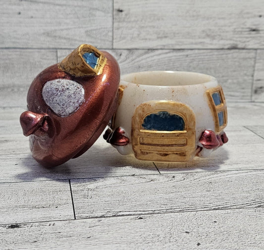 Resin mushroom, white base with gold door and windows, with the red mushroom top, on wooden surface.