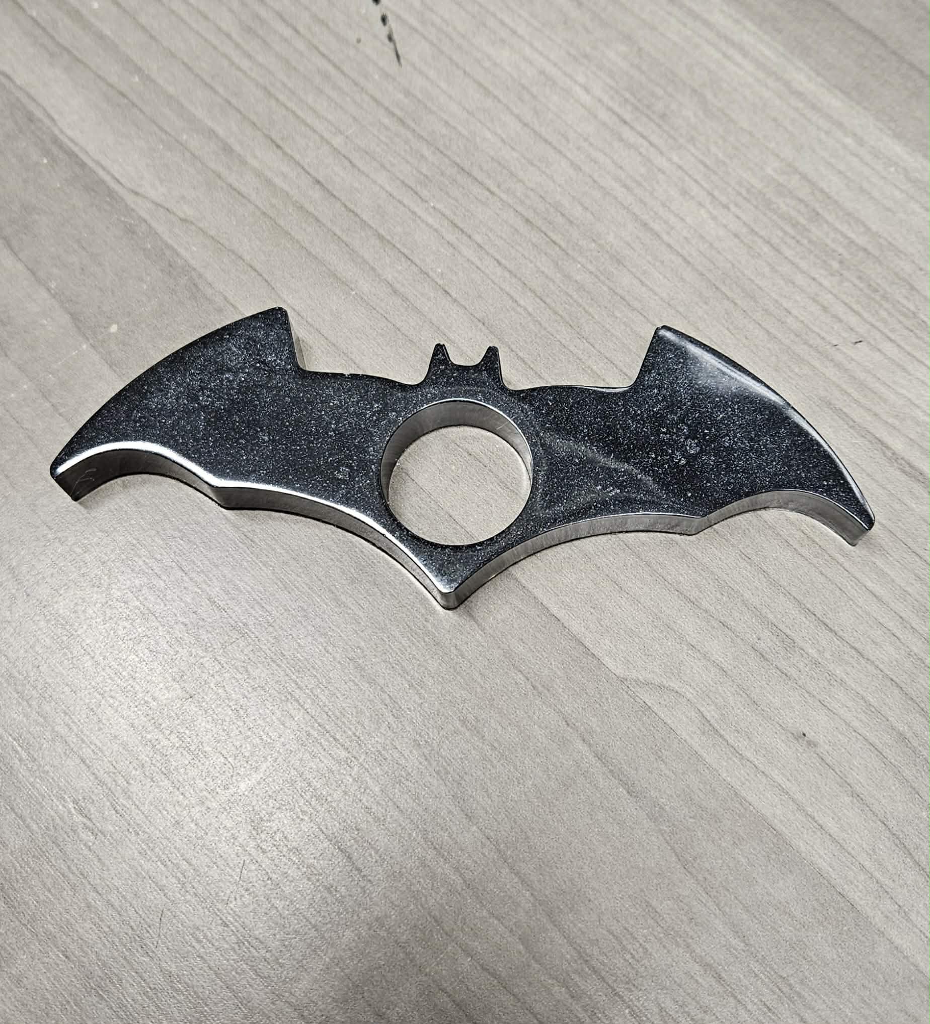 Bat-shaped page holder on a textured gray surface