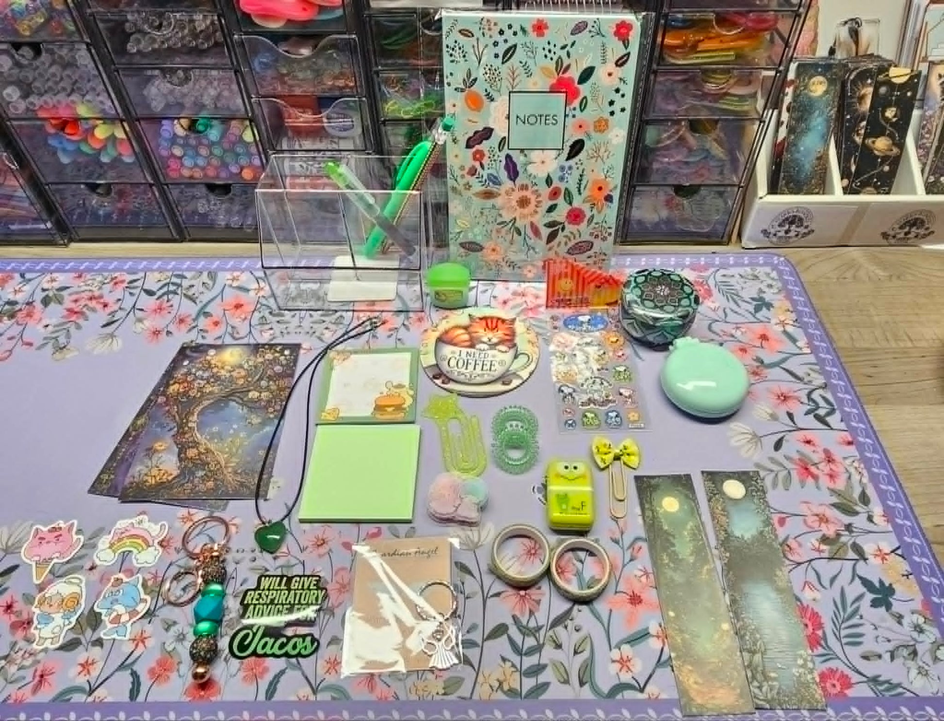 Collection of stationery items on a floral-patterned tablecloth with drawers in the background.