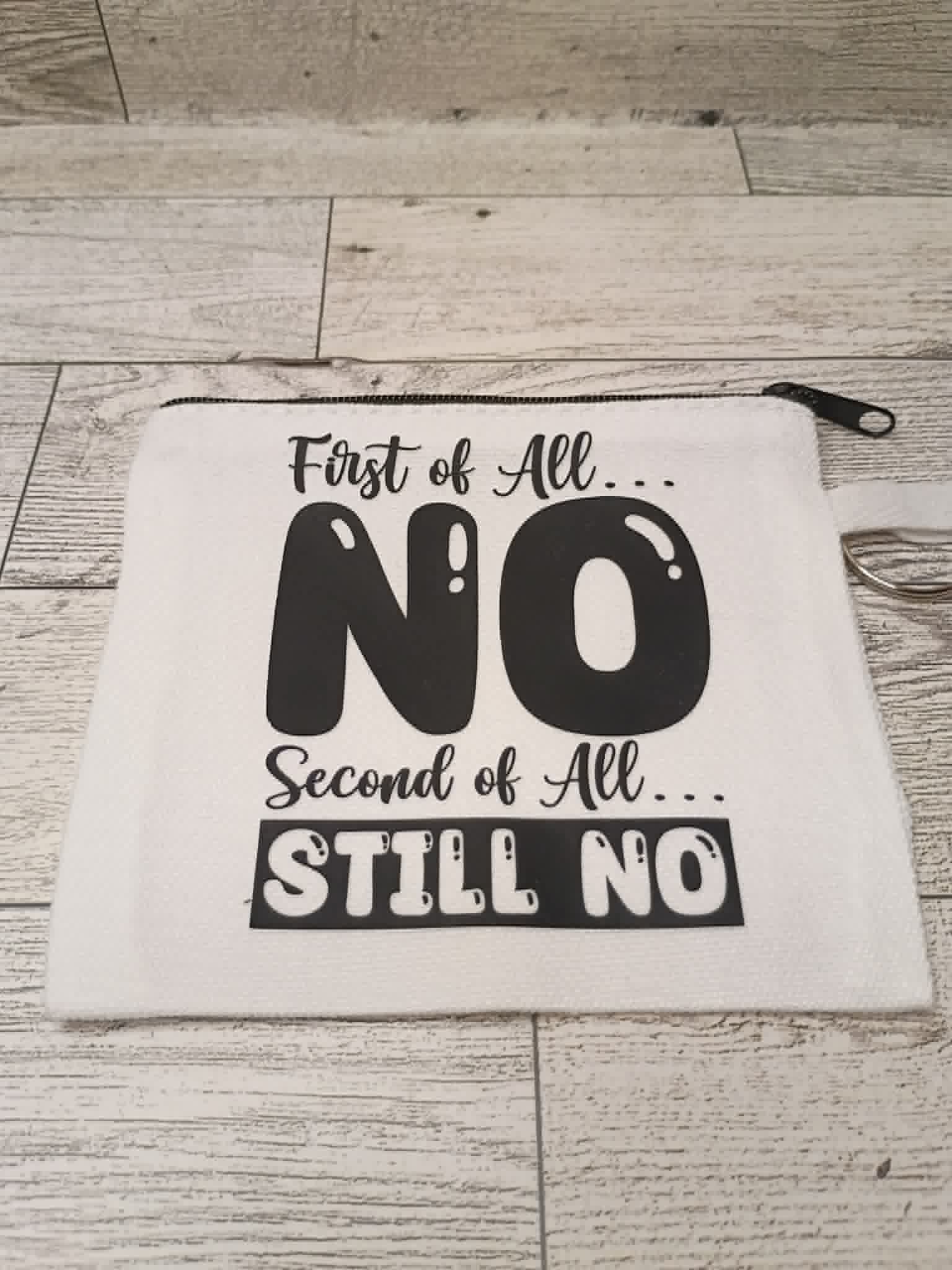 A white fabric zippered pouch with black printed text reading 'First of All.