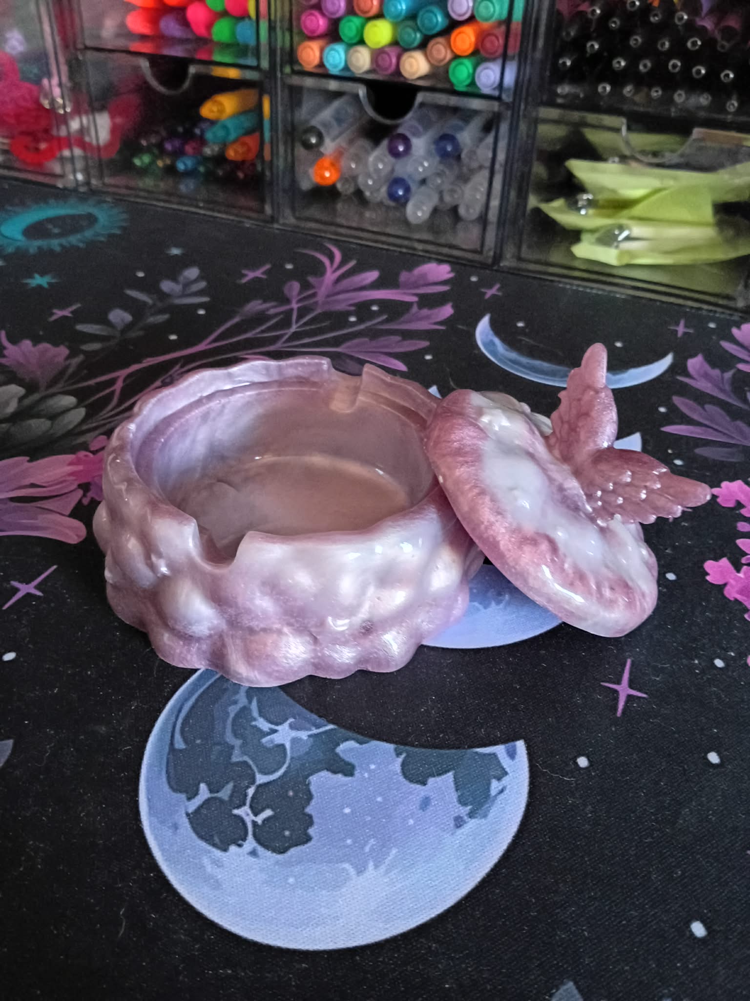 Pink butterfly-shaped container on a decorative surface with colorful markers in the background