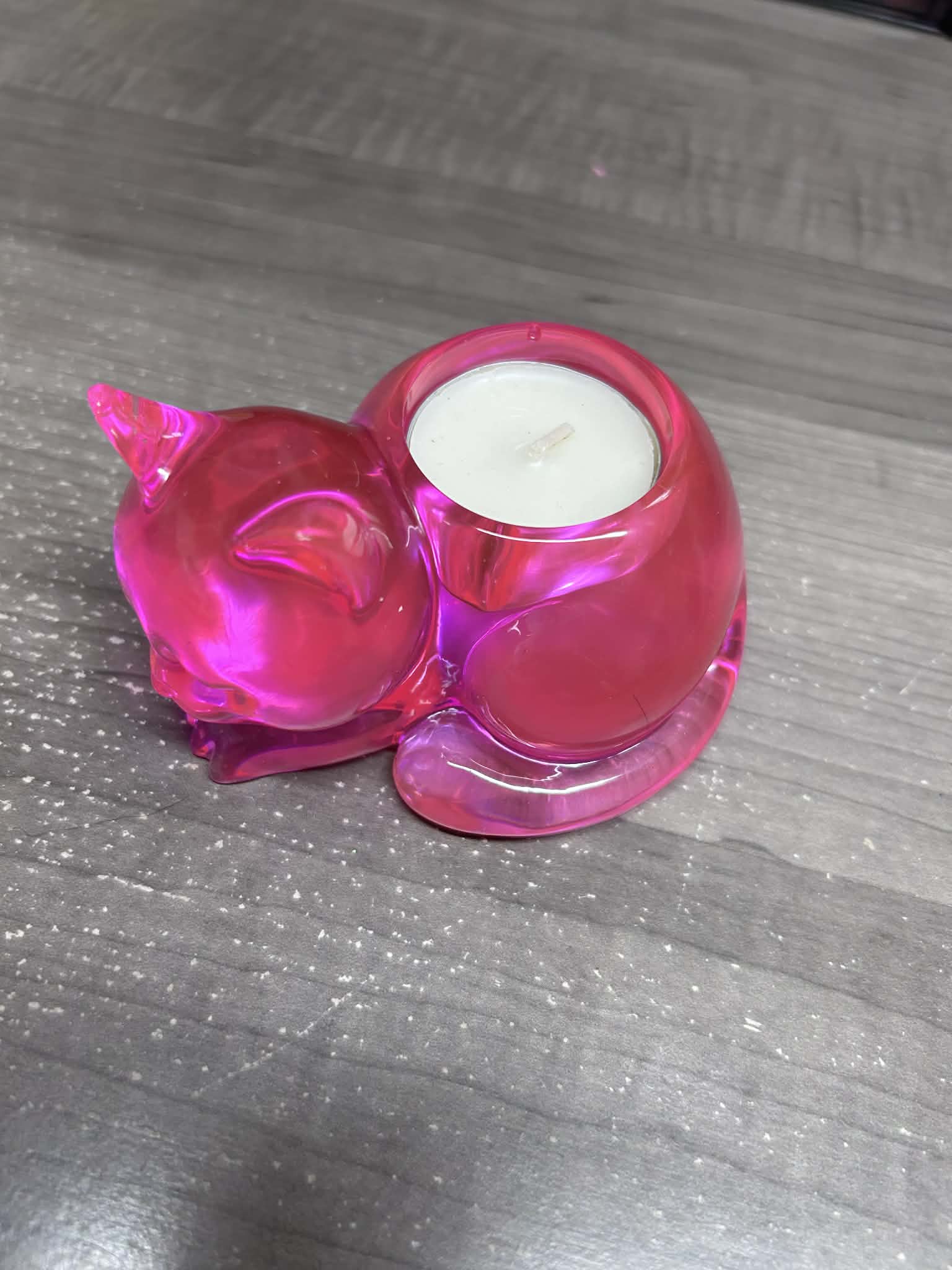 Pink cat candle holder with a white candle on a gray surface