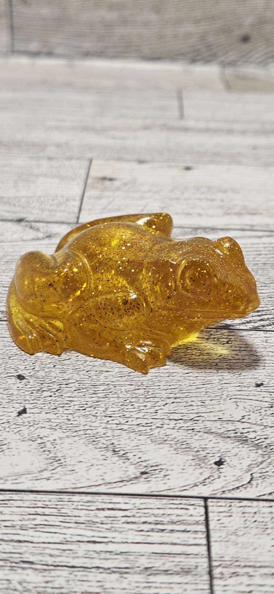Amber-colored frog figurine on a wooden surface