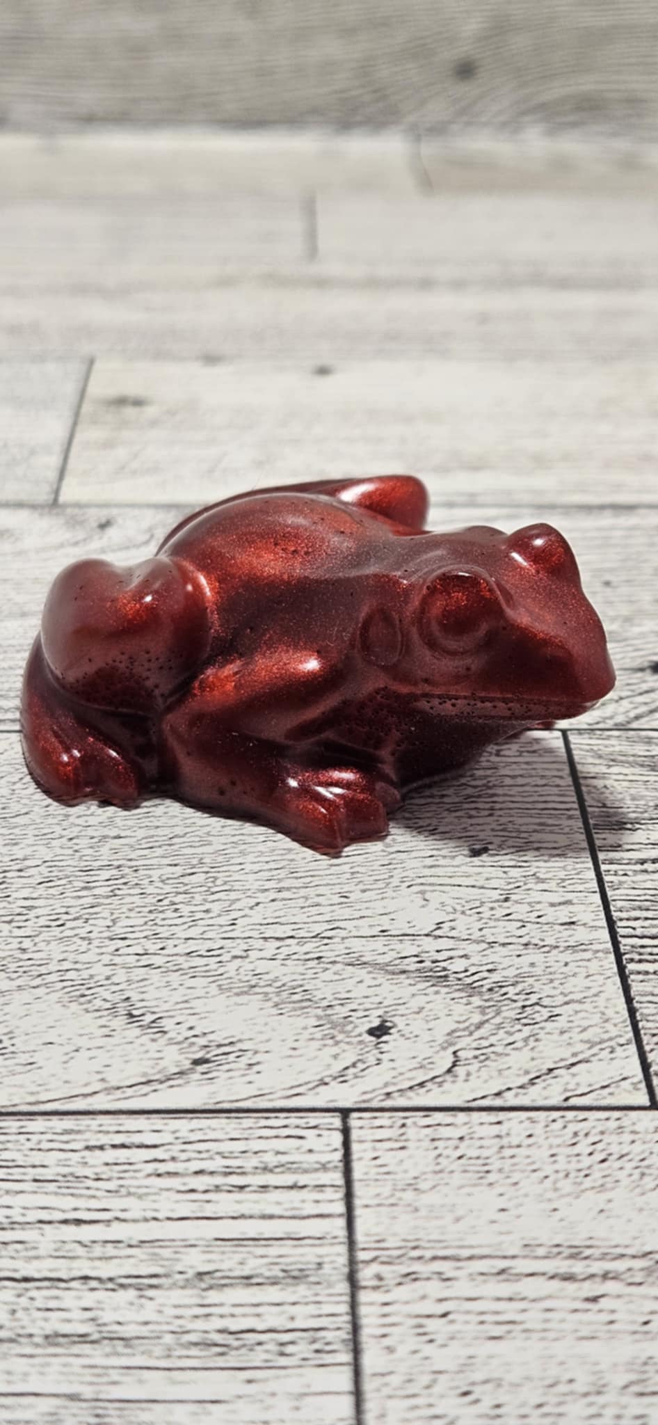 Red frog figurine on a light wooden floor