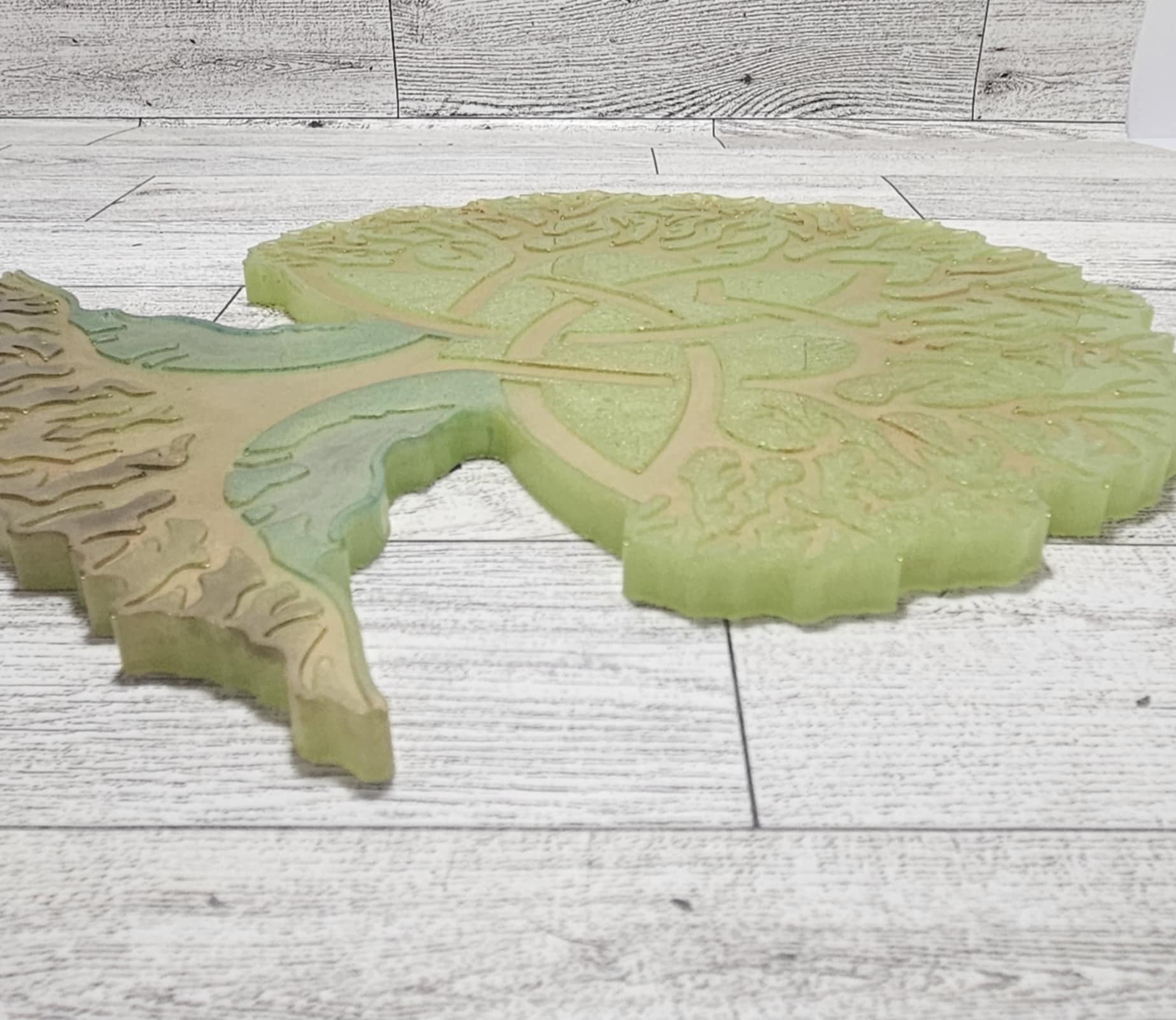 Green and brown textured tree of life wall decor on a wooden surface