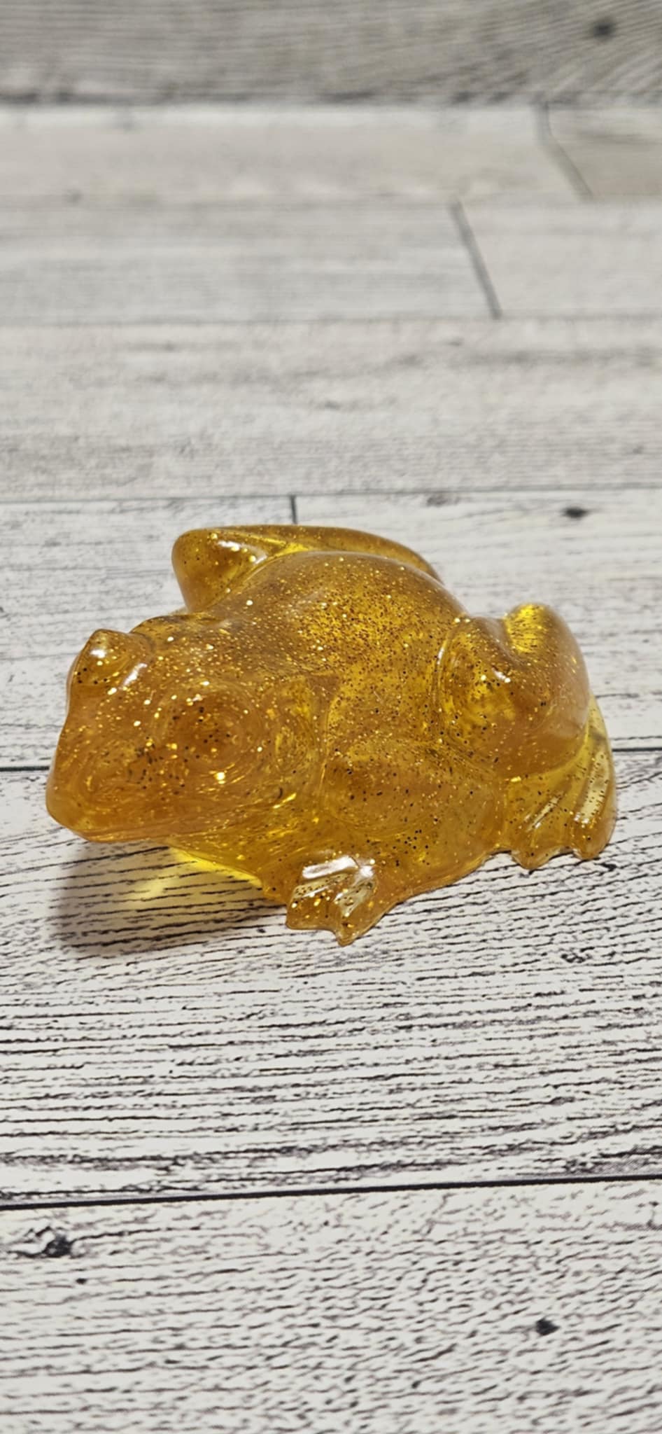 Amber-colored resin frog on a wooden surface