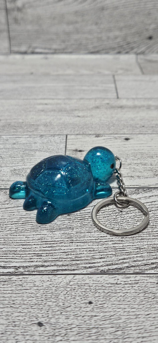 Blue glittery turtle keychain on a wooden surface