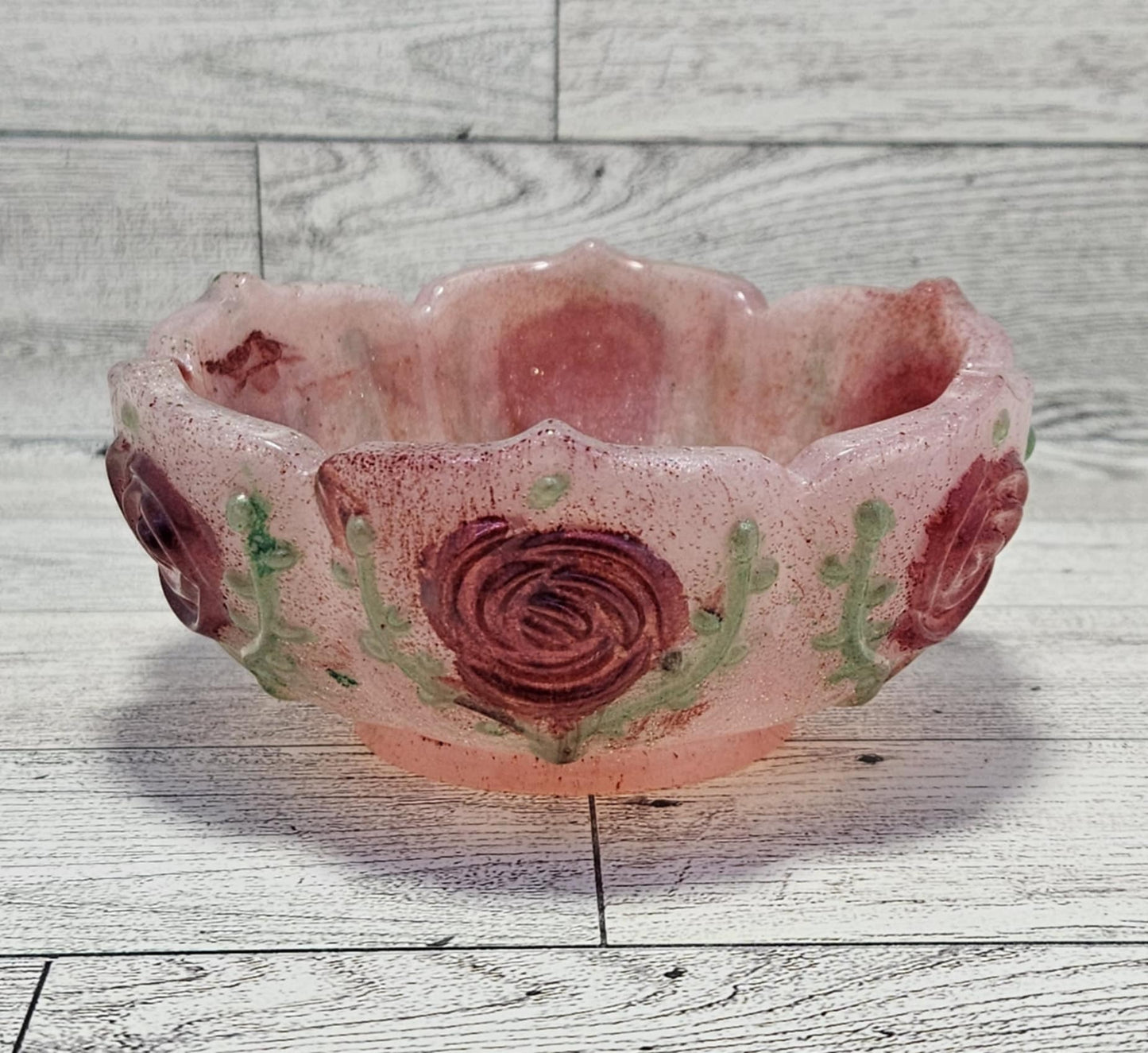 Pink resin bowl with rose designs on a wooden surface