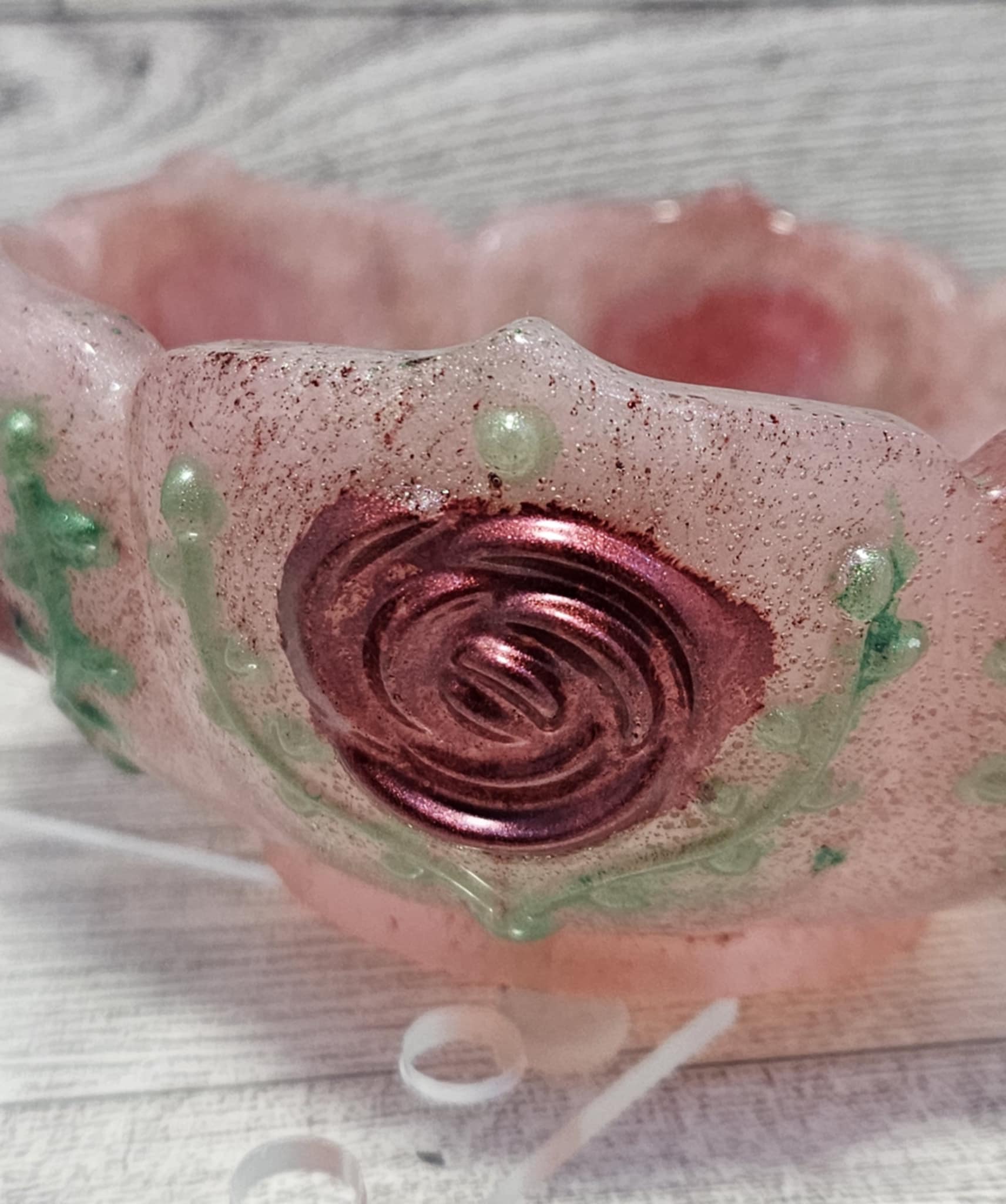 Pink resin bowl with a central swirl design on a textured surface